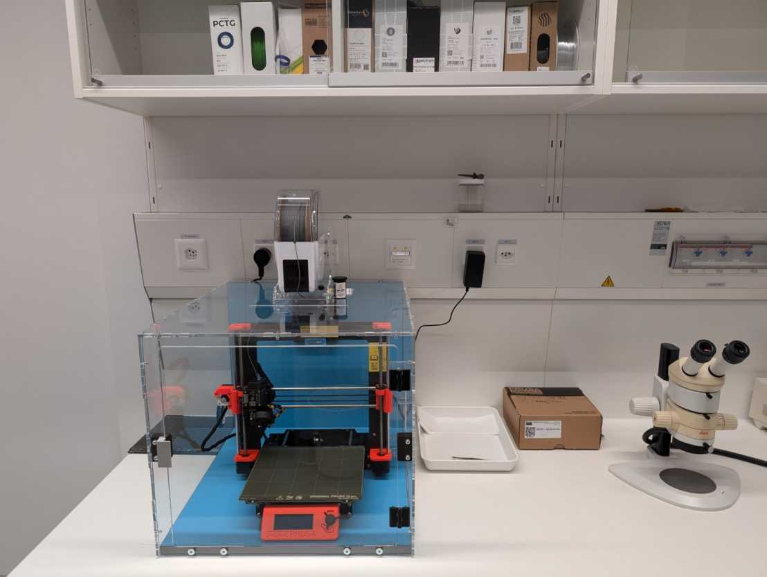 Enlarged view: Photograph of a Prusa 3D printer in an enclosure on a table 