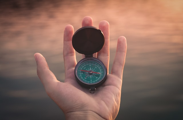 person holding black and green compass pointing to west photo – Photo by Aron Visuals on Unsplash