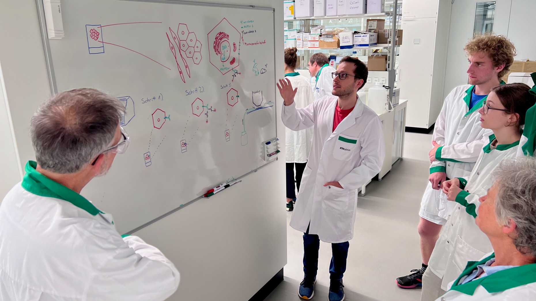 PhD student Marcel Pohly explains antibody-mediated stainings to visitors. 
